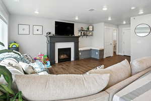 Living area featuring a warm lit fireplace and dark wood-style flooring
