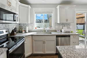 Kitchen with stainless steel appliances, white cabinetry, and decorative backsplash