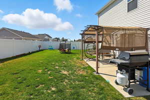 Fenced backyard featuring a patio, a residential view, and a trampoline