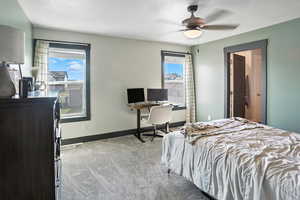 Bedroom featuring an office area, light carpet, a textured ceiling, and ceiling fan