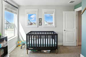 Carpeted bedroom with a nursery area and baseboards