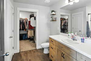 Bathroom with a spacious closet, vanity, and wood finished floors