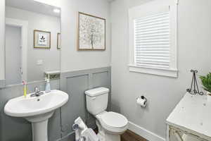 Half bath featuring toilet and wood finished floors