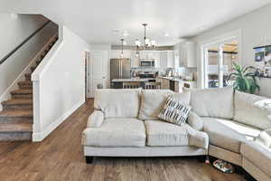 Living room featuring stairs, dark wood-style flooring, and a chandelier