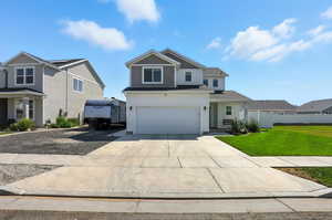 Traditional home with concrete driveway, an attached garage, a front yard, and board and batten siding