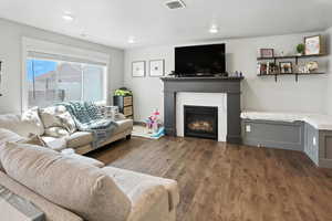 Living area featuring a glass covered fireplace, wood finished floors, a textured ceiling, and recessed lighting
