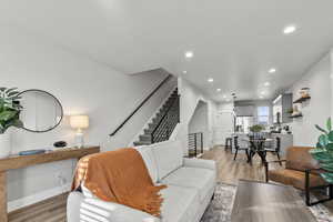 Living room with light wood finished floors, stairway, and recessed lighting