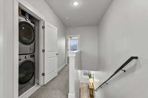 Laundry area with estacked washer and dryer and light carpet