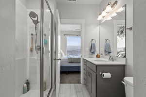 Ensuite bathroom with vanity, a shower stall, and a textured wall