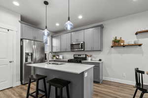 Kitchen featuring gray cabinetry, stainless steel appliances, wood finished floors, and recessed lighting