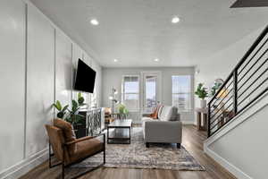 Living room featuring wood finished floors, healthy amount of natural light, stairway, recessed lighting, and a textured ceiling
