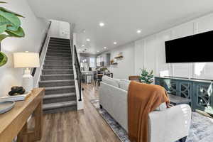 Living area with recessed lighting, wood finished floors, stairs, and a decorative wall