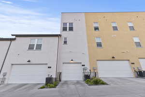 Back of house with an attached garage, driveway, and stucco siding