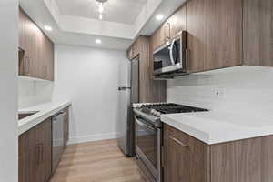 Kitchen featuring stainless steel appliances, light wood looking LVP floors, tasteful backsplash, light countertops, and recessed lighting