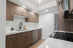 Kitchen featuring light wood-style flooring, light quartz countertops, appliances with stainless steel finishes, recessed lighting, and tasteful backsplash.