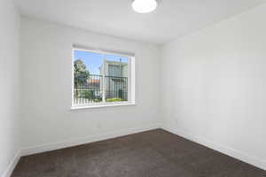 Bedroom 1 featuring dark carpet and natural light.