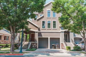 Traditional home with stucco siding, an attached garage, stairs, and concrete driveway