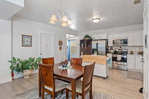 Dining space with light wood finished floors and a chandelier