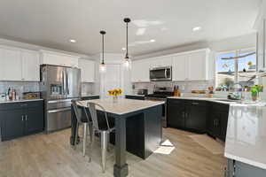 Kitchen with appliances with stainless steel finishes, white cabinets, light countertops, and recessed lighting