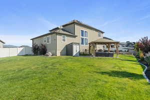 Rear view of property with a fenced backyard, a gazebo, stucco siding, and a storage shed