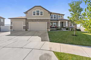 View of front facade with stone siding, concrete driveway, stucco siding, and a garage