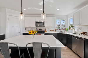 Kitchen with appliances with stainless steel finishes, backsplash, white cabinetry, recessed lighting, and light wood-type flooring