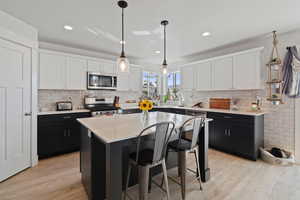 Kitchen featuring dark cabinetry, white cabinets, light wood-style flooring, and recessed lighting