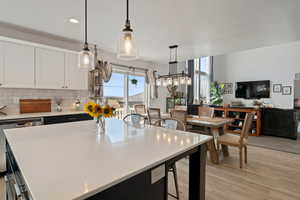 Kitchen with light wood-type flooring, tasteful backsplash, recessed lighting, white cabinets, and a center island
