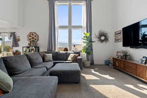Living area featuring a towering ceiling and carpet floors