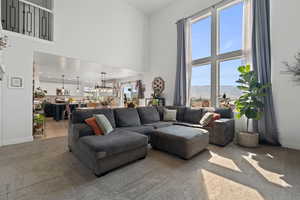 Carpeted living room featuring a towering ceiling and a chandelier