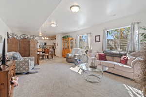 Living area featuring healthy amount of natural light, carpet flooring, and a chandelier