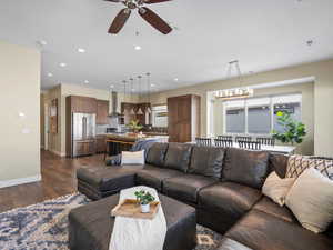 Living area featuring dark wood finished floors, ceiling fan, recessed lighting, healthy amount of natural light, and a chandelier