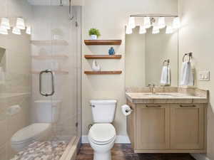 Bathroom featuring vanity, a stall shower, and wood finished floors