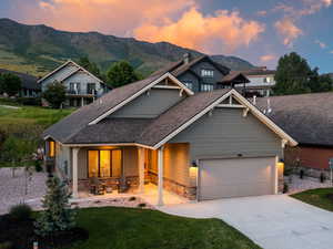 Craftsman house with stone siding, a mountain view, driveway, a garage, and roof with shingles