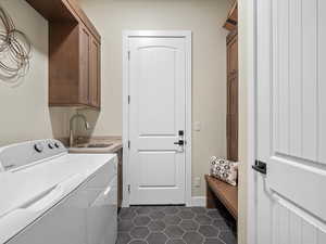 Washroom with cabinet space, washing machine and clothes dryer, and dark tile patterned flooring
