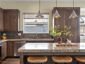 Kitchen with stainless steel dishwasher, a breakfast bar area, and decorative light fixtures