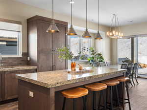 Kitchen featuring healthy amount of natural light, a kitchen island, tasteful backsplash, and a breakfast bar area