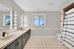 Full bath featuring double vanity, tile patterned flooring, backsplash, and curtained shower