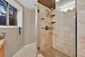 Bathroom with tile patterned floors, a tile shower, and vanity