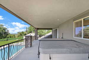 Balcony featuring a hot tub and view of pool area