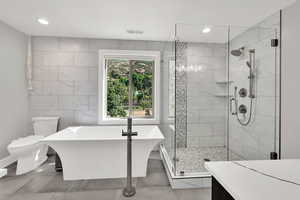Full bath with a freestanding tub, tile walls, a stall shower, and recessed lighting