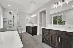 Bathroom with a shower stall, two vanities, recessed lighting, and a freestanding bath