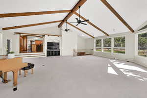 Unfurnished living room with beamed ceiling, carpet floors, and high vaulted ceiling