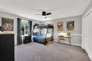 Carpeted bedroom featuring a ceiling fan and a closet