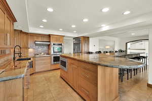 Kitchen with a kitchen bar, recessed lighting, light tile patterned flooring, a spacious island, and decorative backsplash