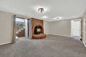 Unfurnished living room featuring carpet, stairway, and a large fireplace
