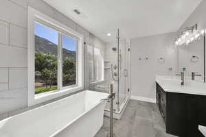 Bathroom with a freestanding bath, a mountain view, vanity, a stall shower, and recessed lighting