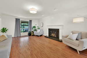 Living area with crown molding, light wood-type flooring, and a premium fireplace