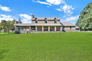 View of front of property with stone siding, a chimney, a front yard, and stucco siding