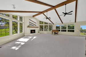 Unfurnished living room with beam ceiling, a fireplace, high vaulted ceiling, carpet, and ceiling fan